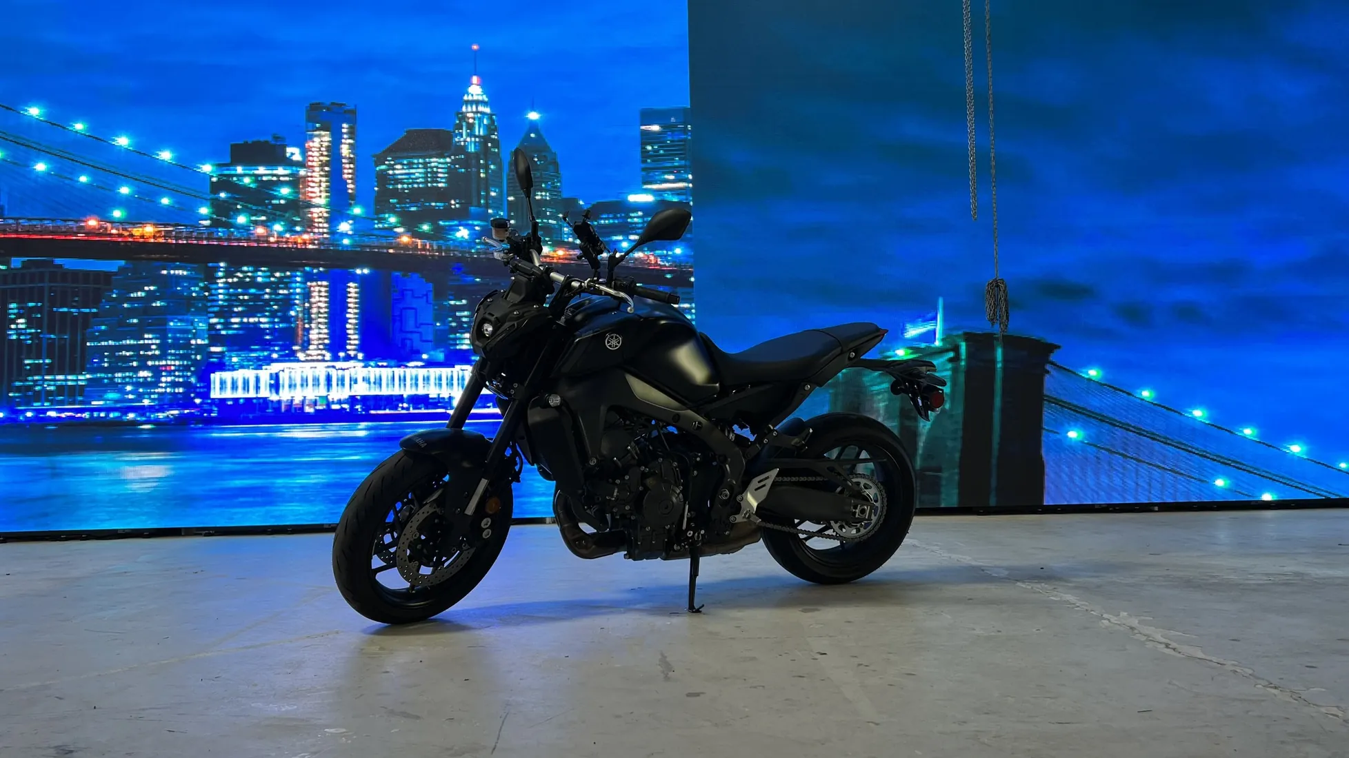 A motorcycle in front of an LED wall showing a city skyline at night.