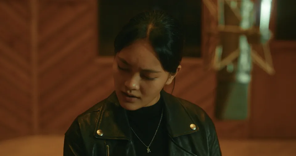 Music video still filmed at Power Station at BerkleeNYC in Hell’s Kitchen, NYC: a close-up of a singer in a leather jacket at a vintage microphone